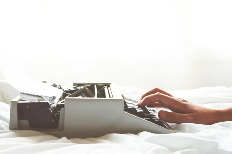 Manos escribiendo en una máquina de escribir antigua
